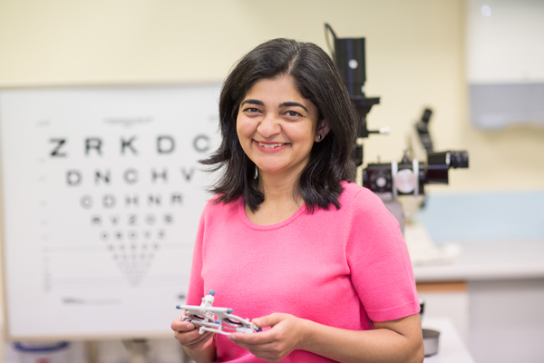 Smiling woman next to an eye chart