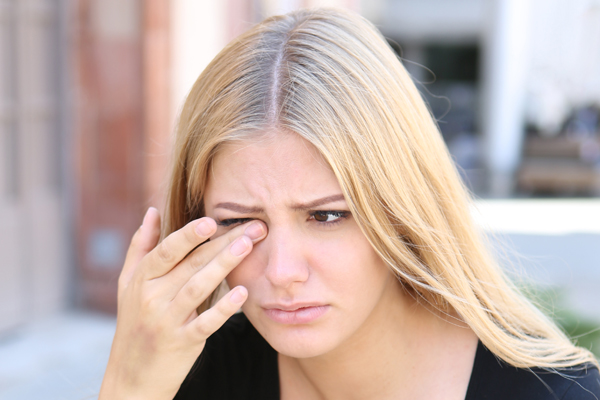 Woman with eye pain holding a finger to her eye
