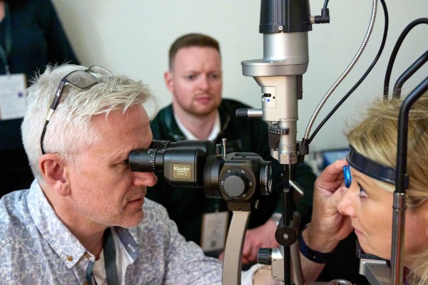 A patient undergoing an eye examination, with a clinician holding a lens in front of their eye.