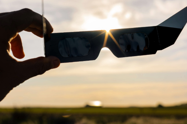 Person using certified solar eclipse glasses to protect their eyes while watching a partial eclipse