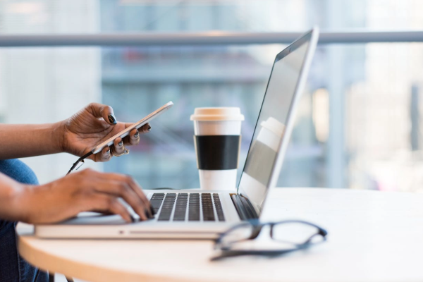 Person working on a laptop with a phone and coffee nearby