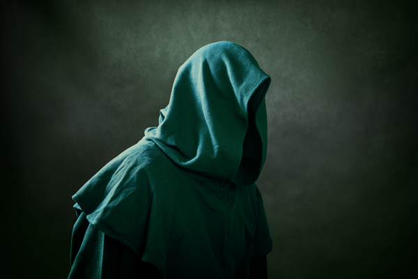 A hooded, faceless figure in a teal cloak against a dark background.